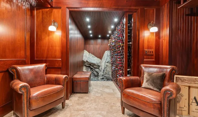Wine cellar entrance with leather armchairs and wood paneling — Deep River, CT residence